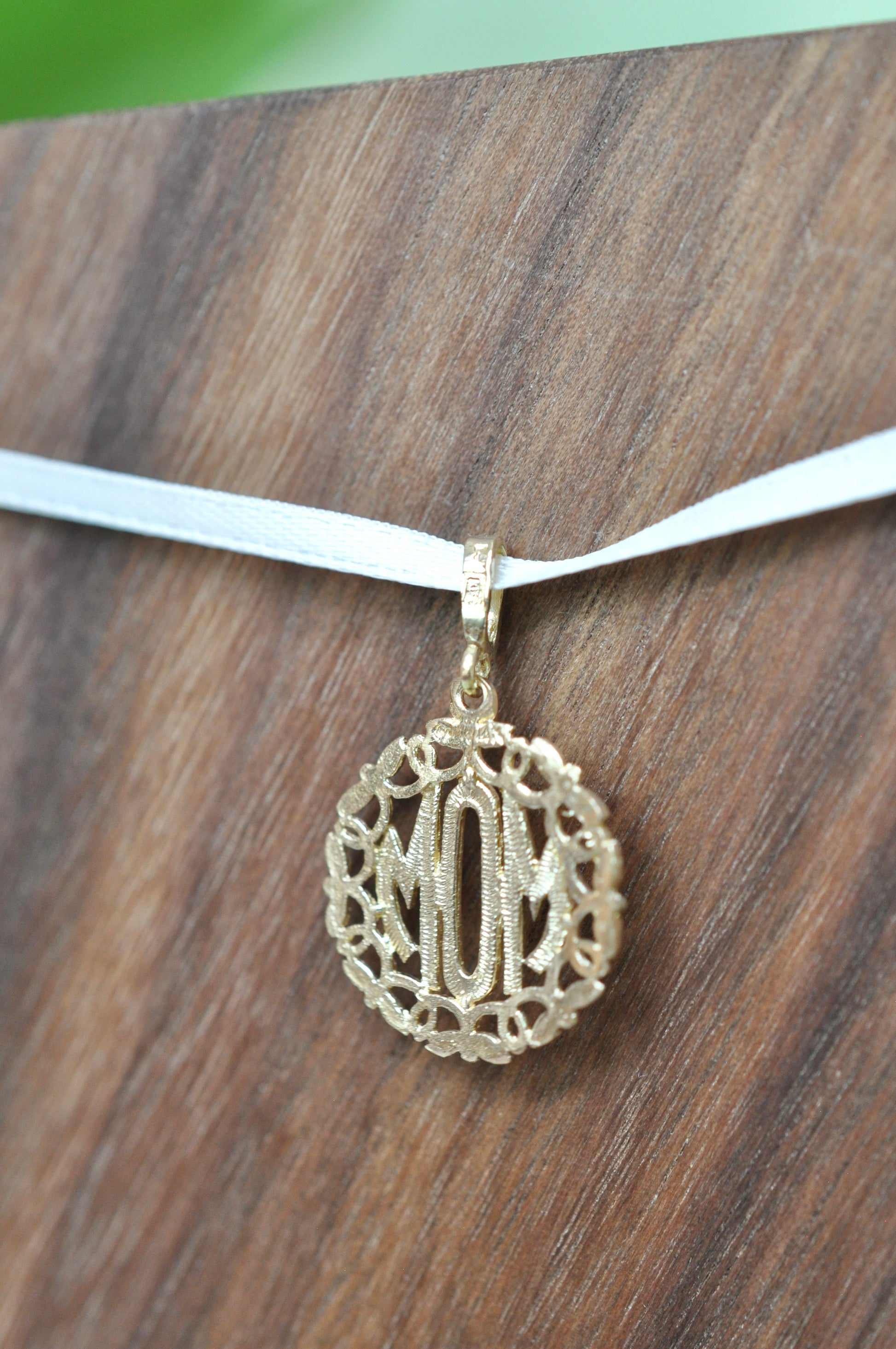 Mom pendant encased in 14kt yellow gold wreath with floral detailing, approximately 18mm wide, 20mm long, 1.78g