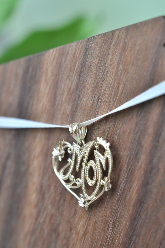 Mom encased in heart with scroll and diamond-cut detailing in 14kt yellow gold, approximately 23mm wide, 20mm long, 1.66g