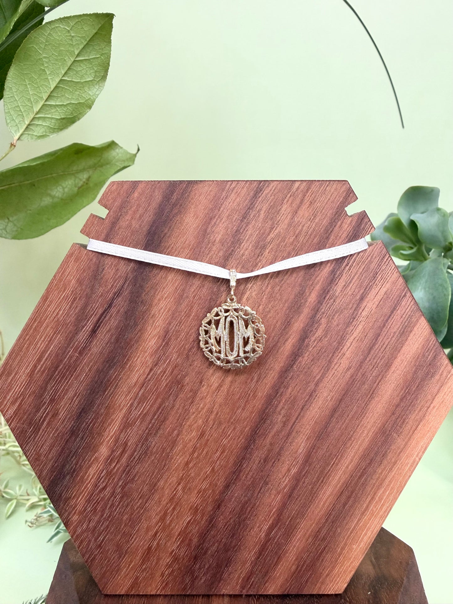 Mom pendant encased in 14kt yellow gold wreath with floral detailing, approximately 18mm wide, 20mm long, 1.78g